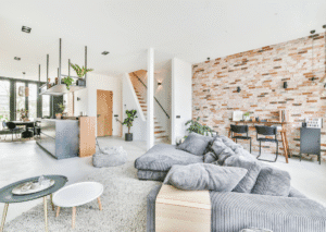 nowoczesny salon cegła na ścianie kolor szary w salonie nowoczesny dom kanapy kuchnia z wyspą okrągłe stoliki dom dla rodziny